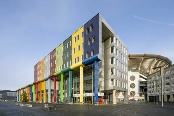 Kleurrijk kantoorgebouw aan de Johan Cruijff Boulevard met de Johan Cruijff ArenA op de achtergrond.